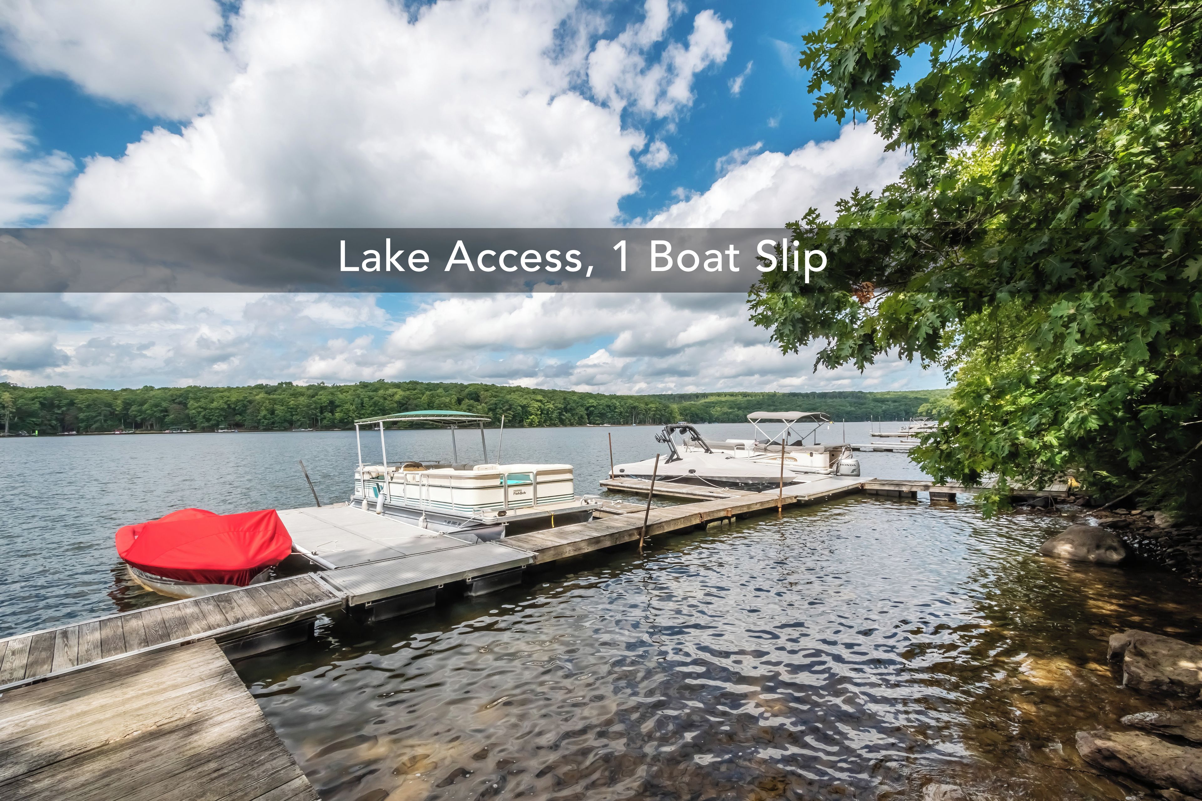 A lake with a dock, a boat slip, and a red boat covered with a canopy.