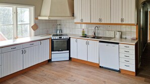 Une cuisine avec des meubles blancs, une cuisinière, un lave-vaisselle et une fenêtre.