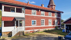 Un bâtiment en briques rouges, doté d’un balcon blanc, d’une cheminée et d’une tour.
