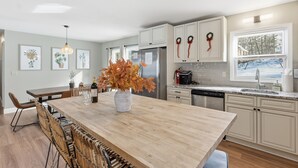 A modern kitchen with a central island, white cabinetry, and a view of the outdoors.