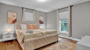 A bedroom with a large bed, bedside tables, and artwork on the walls.