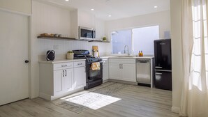 Una cocina moderna con armarios blancos, un refrigerador negro, un microondas y una estufa.