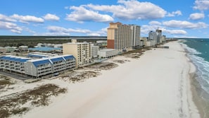 A beachfront hotel with multiple buildings, including a large hotel with a red roof and several smaller structures.