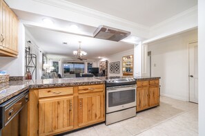 A spacious kitchen with wooden cabinets, a stainless steel stove, and granite countertops.