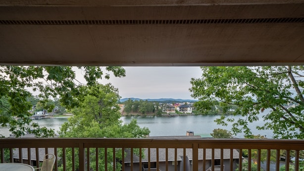 Blick vom Balkon auf einen See mit Häusern im Hintergrund.