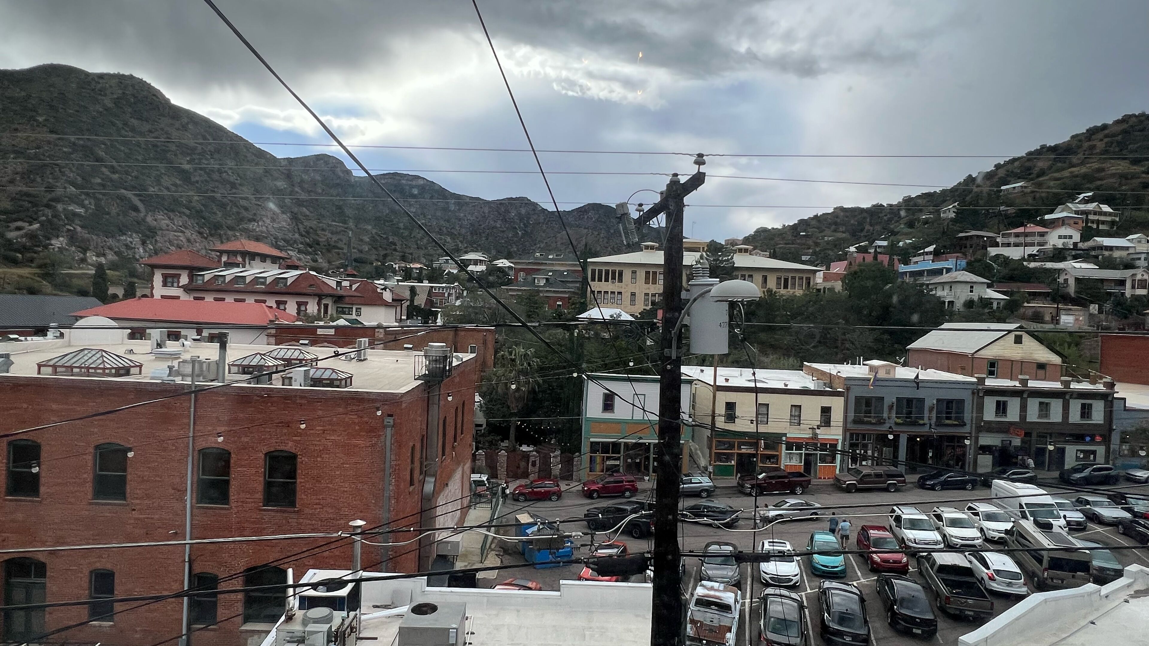 A town with buildings, a parking lot, and a mountainous backdrop.