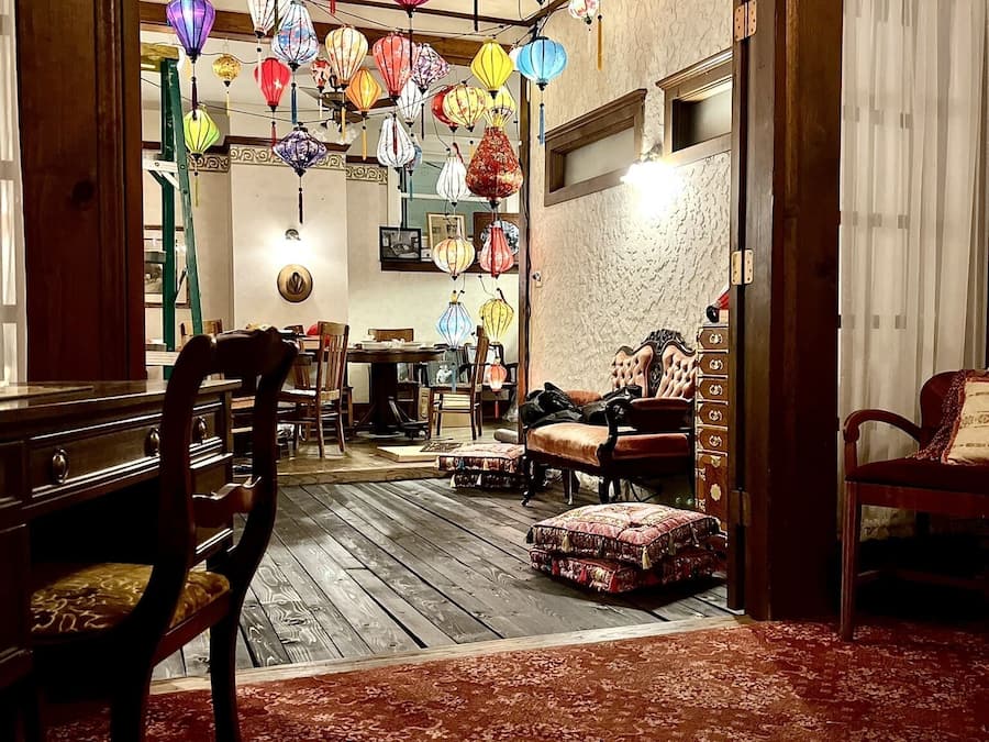 Una habitación con piso de madera, alfombra roja y un comedor con sillas y una mesa.