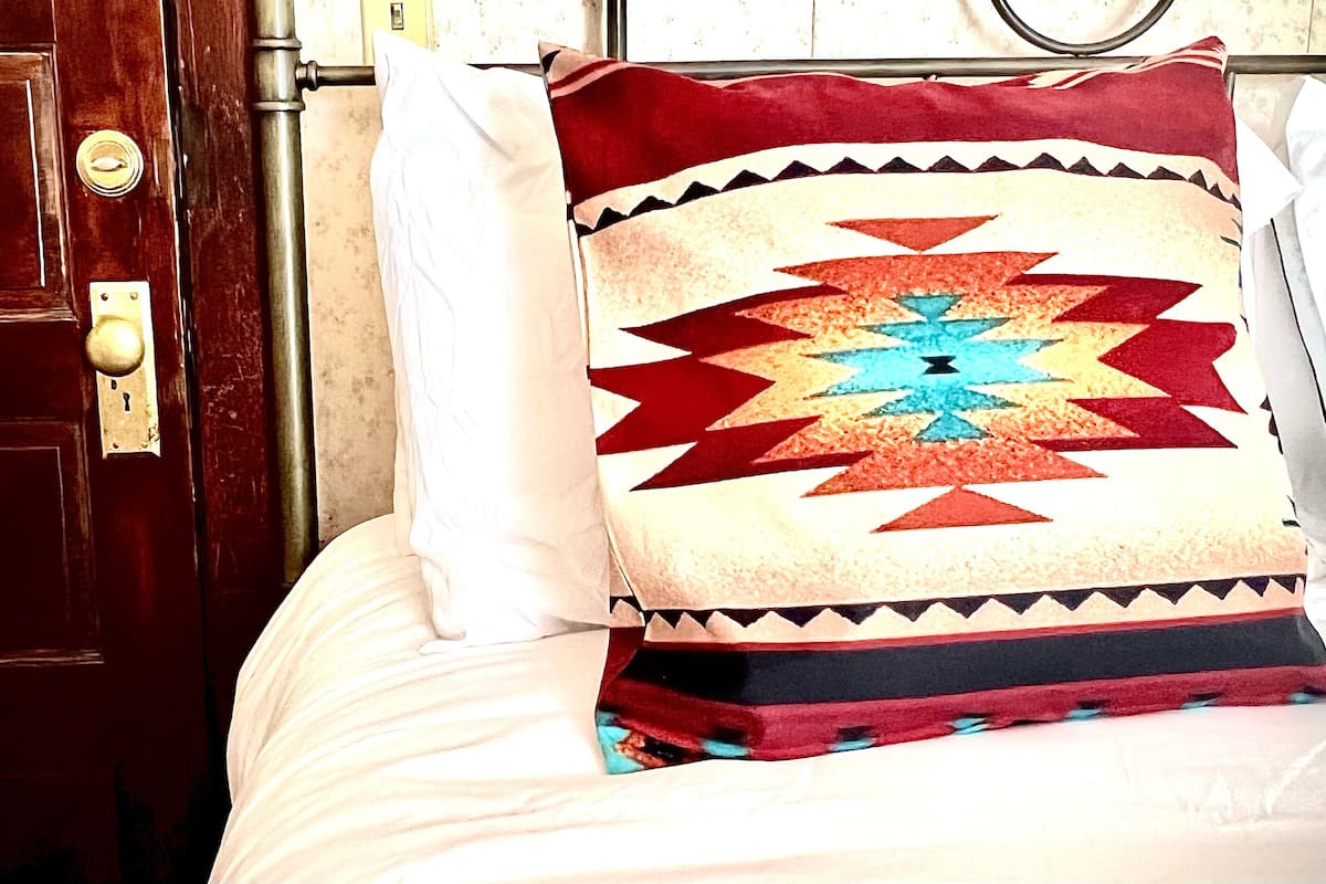 A bed with a decorative pillow featuring a geometric pattern.