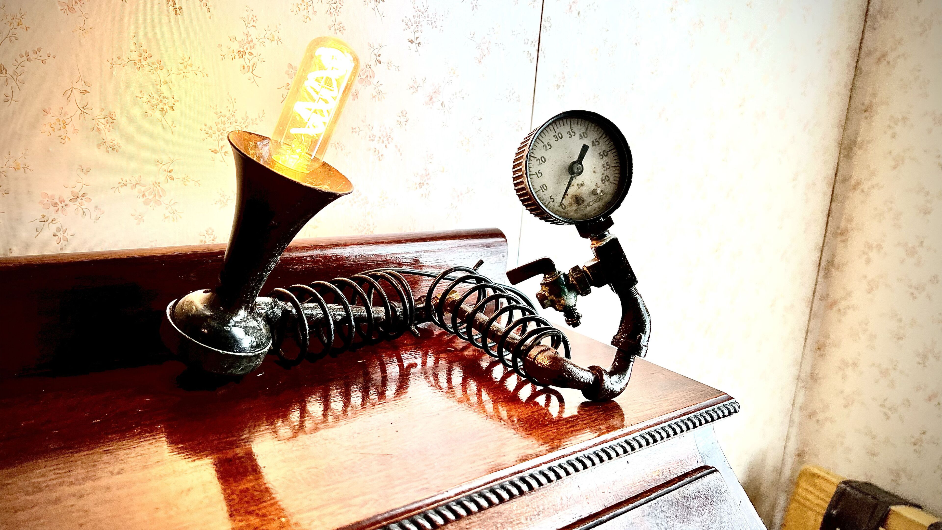 Un appareil mécanique ancien, doté d’une ampoule en verre et d’un manomètre, posé sur une surface en bois.