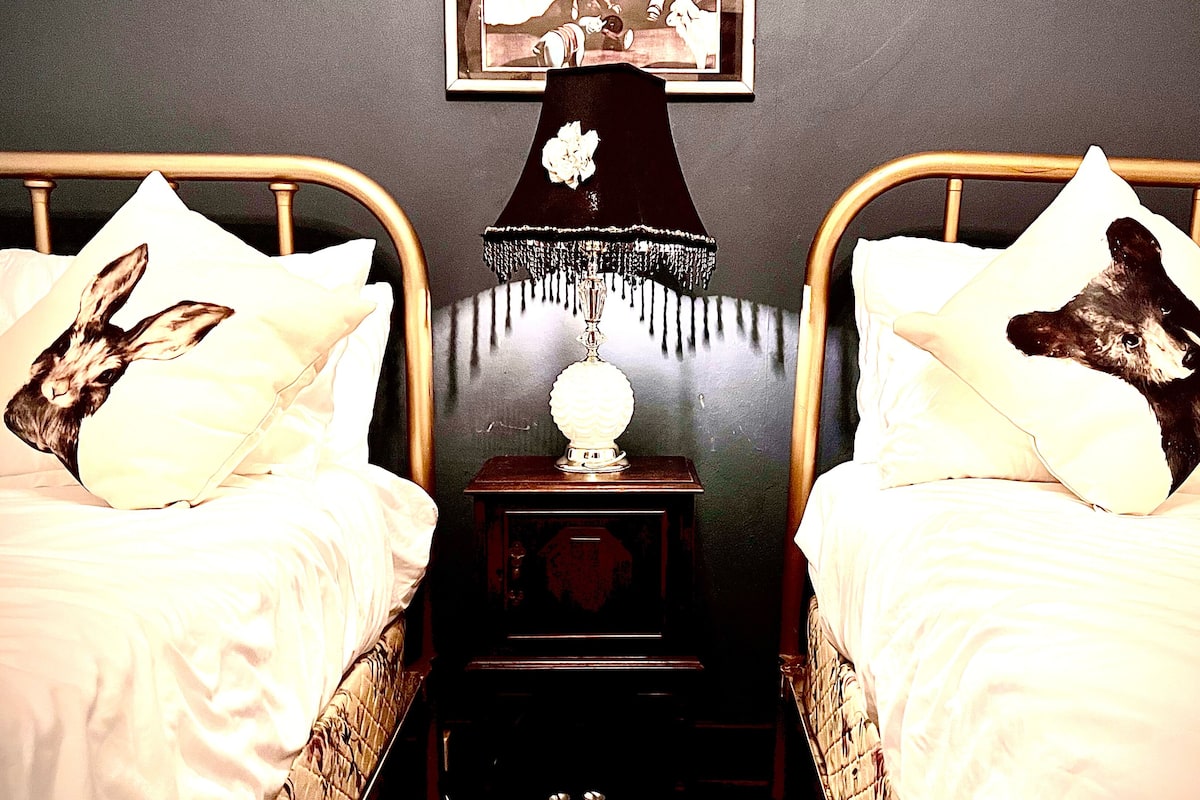 A bedroom with two beds, each with a pillow featuring a rabbit design. There is a nightstand with a lamp between the beds.