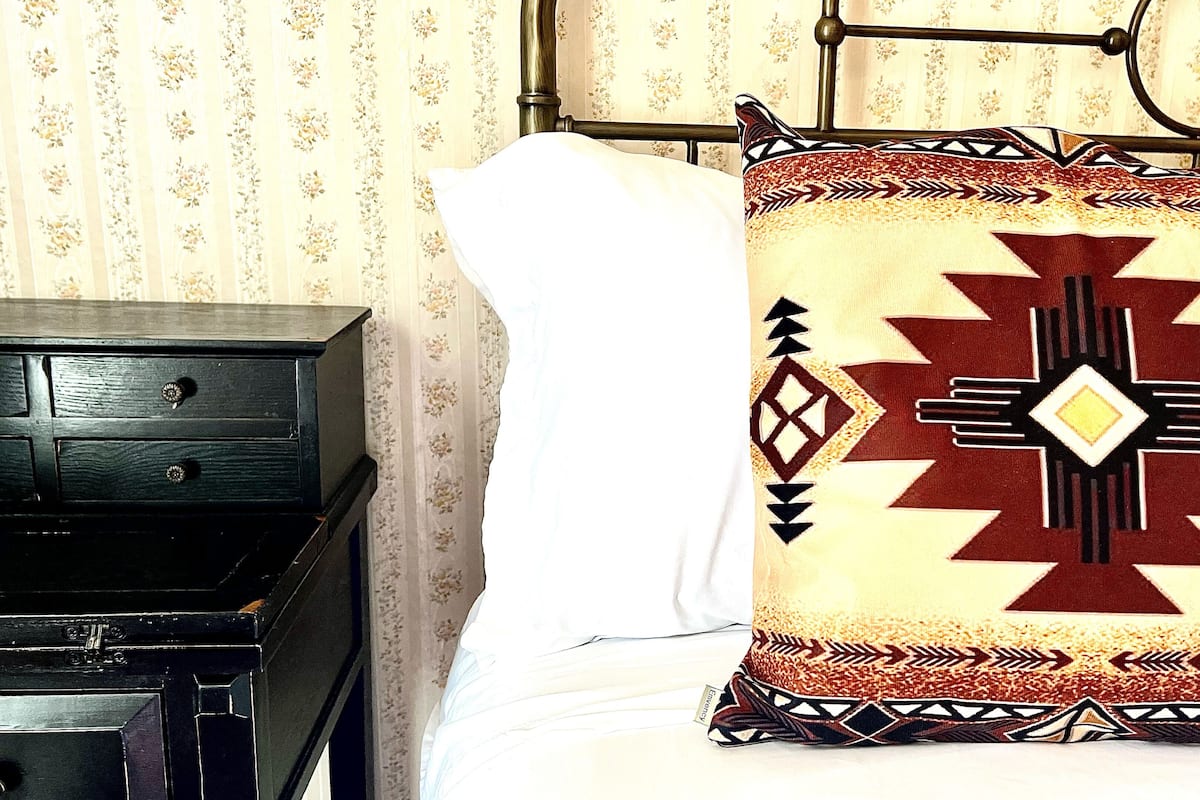 A bed with a patterned pillow and a wooden nightstand.