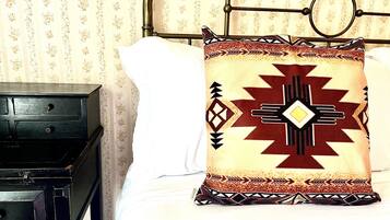 Uma cama com travesseiro estampado e uma mesa de cabeceira de madeira.
