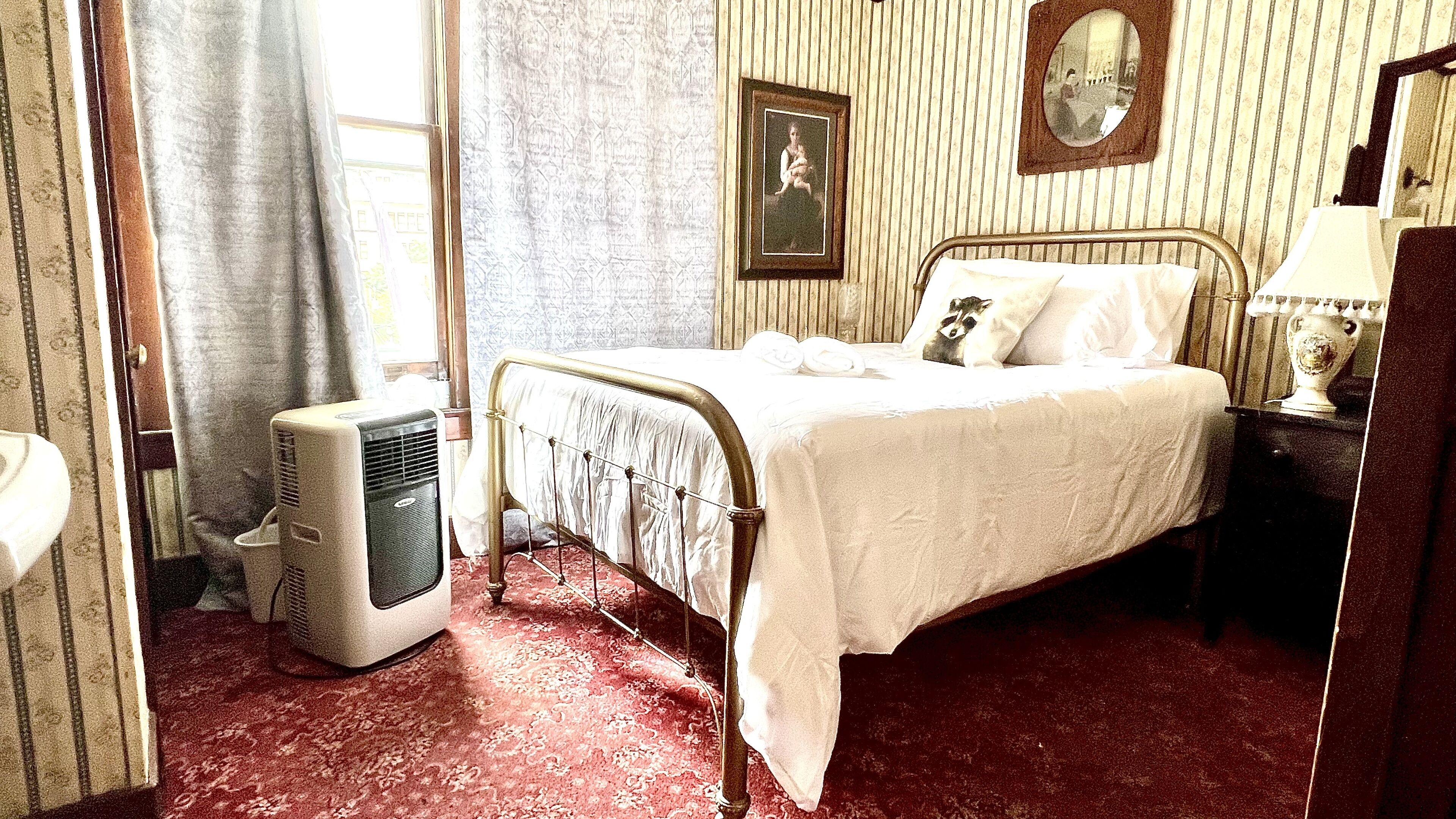 Ein Zimmer mit einem Bett, einem Heizkörper, einem Spiegel und einem gerahmten Bild an der Wand.