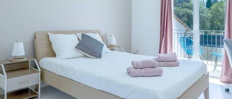 Une chambre à coucher moderne avec un lit en bois, une literie blanche et deux tables de chevet avec des lampes.
