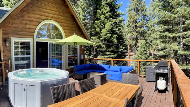 Eine Holzterrasse mit Whirlpool, einem Holztisch und blauen Sitzmöglichkeiten.