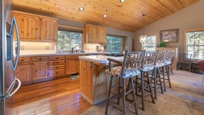 Eine Küche mit Holzschränken, einem Edelstahlkühlschrank und einer Bar mit Holzhockern.