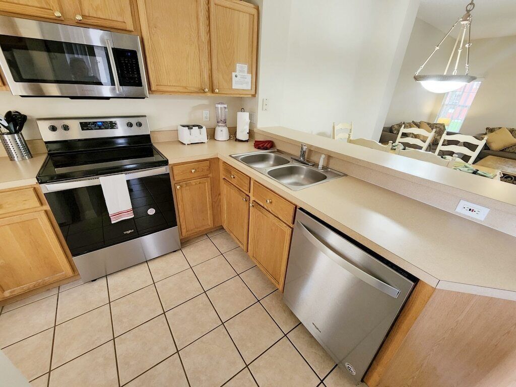 A modern kitchen with wooden cabinets, stainless steel appliances, a dishwasher, and a large window.