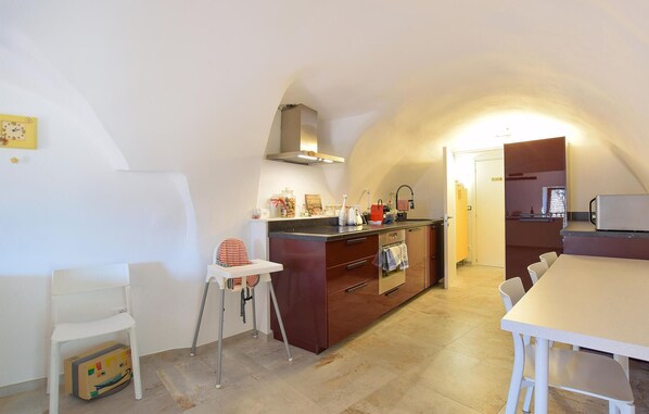 Una cocina compacta con una isla central, una pequeña mesa de comedor y un techo alto.