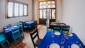 Comedor con mesas dispuestas para cuatro, manteles azules y sillas.