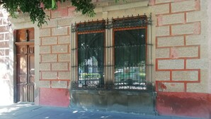 Fachada de edificio con una ventana que presenta rejas de hierro decorativas y una puerta de madera.