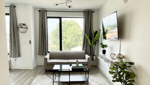 Uma sala de estar moderna com sofá, mesa de centro e uma janela grande.