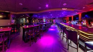 Uma área de bar com vários arranjos de assentos e um balcão.