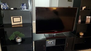 Un televisor de pantalla plana sobre un moble de televisió negre amb un petit armari a sota.