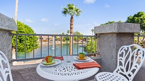 En balkon med et bord dækket til to, med udsigt over vand og en palme.