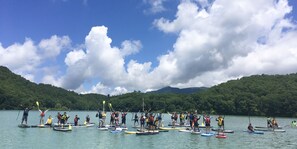 A group of people on paddleboards in a lake surrounded by hills.