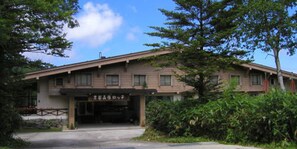 A two-story building with a flat roof and a covered entrance.
