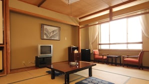 Une pièce de style japonais traditionnel, avec un sol recouvert de tatamis, une table basse, un téléviseur et un tableau encadré accroché au mur.