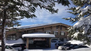 Un bâtiment dont le toit est recouvert de neige, avec des voitures garées devant.