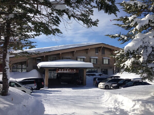 A building with a snow-covered roof and parked cars in front.