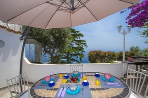Une table ronde recouverte de carreaux, entourée de chaises, placée sous un grand parasol.