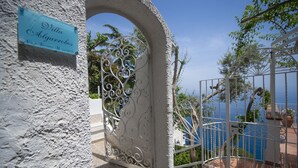 Um portão de ferro forjado com uma placa que diz 'Villa Aljarquobos' e vista para o mar.
