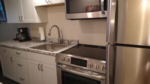 A modern kitchen with stainless steel appliances, including a microwave, oven, and refrigerator. - Clothing Optional Home Away From Home (Lutz)