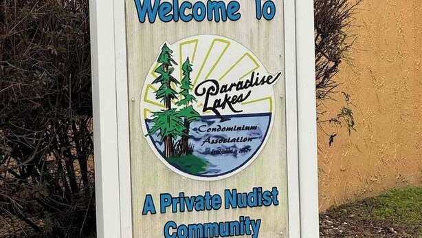 A welcome sign for Paradise Lakes, a private nudist community, with a logo featuring trees and a lake. - Clothing Optional Home Away From Home (Lutz)