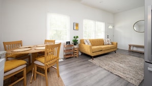 Un salon moderne avec un coin repas, comprenant un canapé, des fauteuils, une table basse et un tapis.