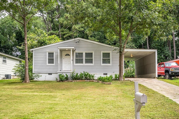 A single-story house with a garage, surrounded by trees and a well-maintained lawn.