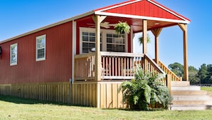 Un bâtiment rouge doté d’une terrasse en bois et d’un porche abrité.