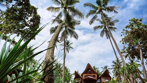 A tropical resort with wooden villas, lush greenery, and palm trees. - The Cove Bali by Nakula (Selemadeg)