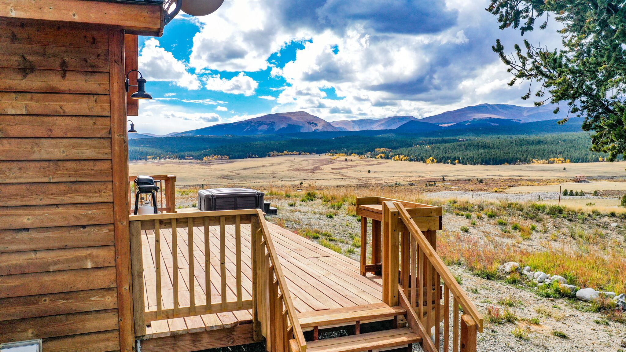 A wooden deck with a view of mountains and a forest.
