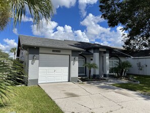 Una casa residencial con garaje, entrada para coches y un césped bien cuidado.