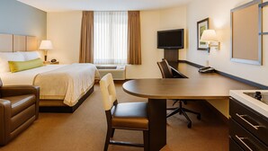 Hotellihuone, jossa on sänky, työpöytä, tuoli, televisio ja lamppu.