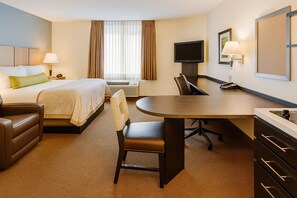 Una habitación de hotel con cama, escritorio, silla, televisión y lámpara.