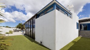 Um edifício moderno com amplas janelas de vidro, telhado plano e gramado bem cuidado.