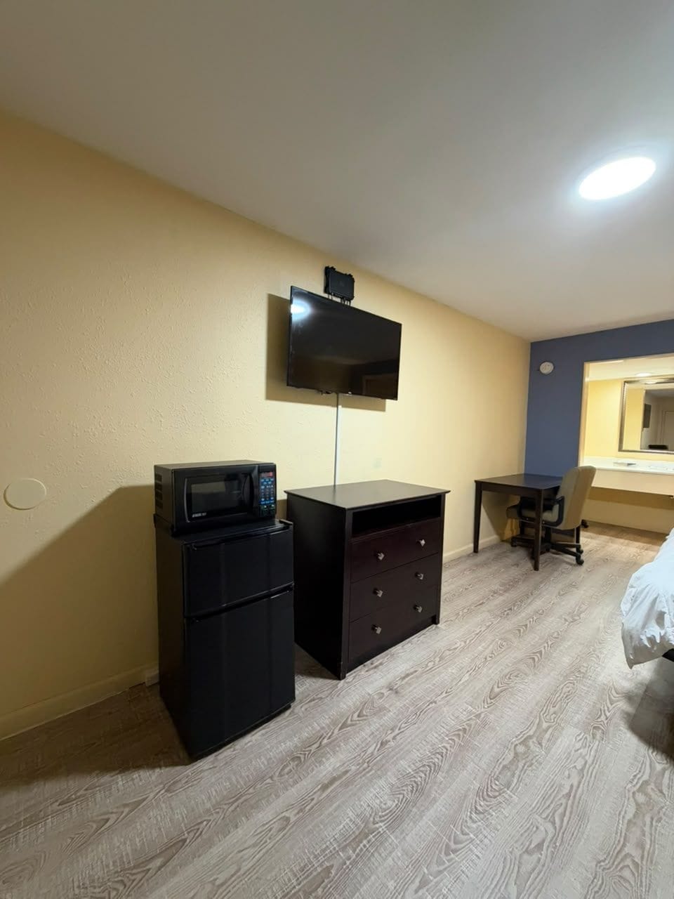 A compact room with a desk, a microwave, and a chair.