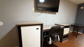 Un espacio de trabajo compacto con escritorio, silla y un refrigerador pequeño.