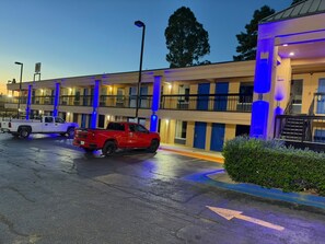 Un motel con varias habitaciones, un estacionamiento y una camioneta roja estacionada al frente.