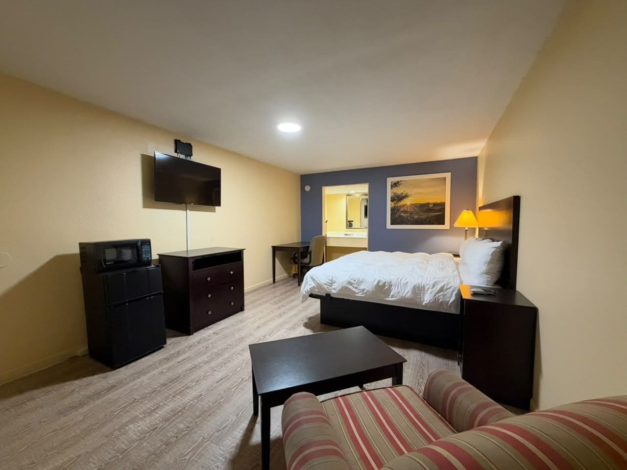 Une chambre d’hôtel équipée d’un lit, d’un bureau, d’une chaise, d’une télévision et d’un four à micro-ondes.